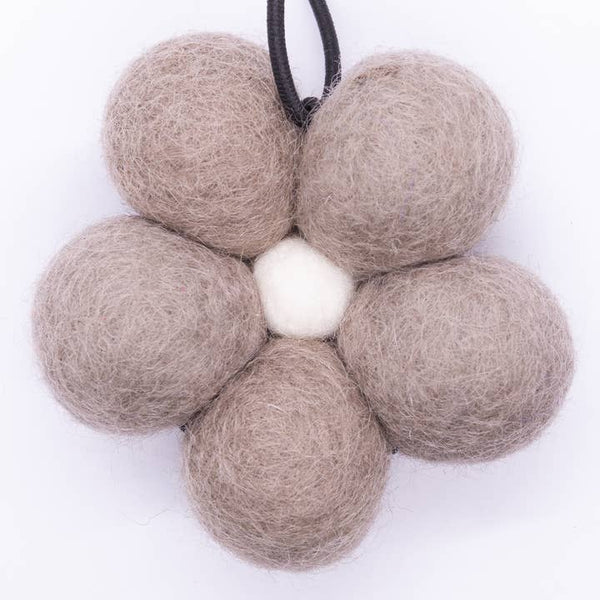 Flower-shaped decorative item made of beige felt balls on a white background