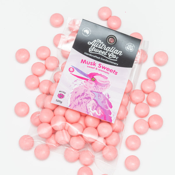 Pink candy balls with a packaging labeled 'The Australian Sweet Co. Musk Sweets' on a white background.