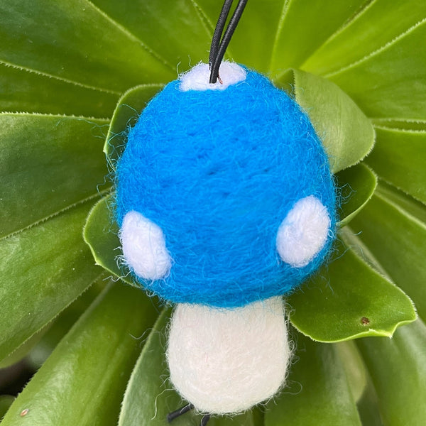 Blue and white mushroom-shaped toy on a green leaf background