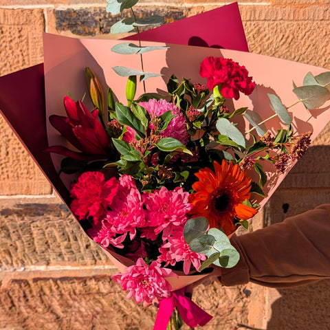 Bouquet of flowers held by a person against a stone wall
