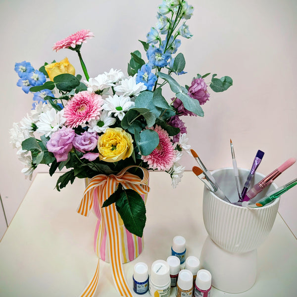 Bouquet of flowers with a striped ribbon next to art supplies on a table as a promotion for Twig & Bloom Easter Workshops