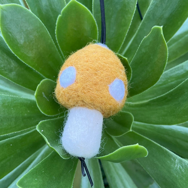 Small plush mushroom toy on a green leafy plant