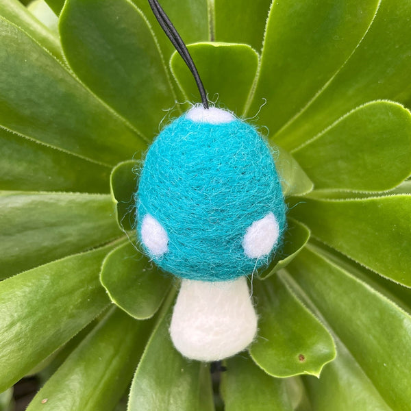 Teal and white mushroom-shaped toy on green leaves