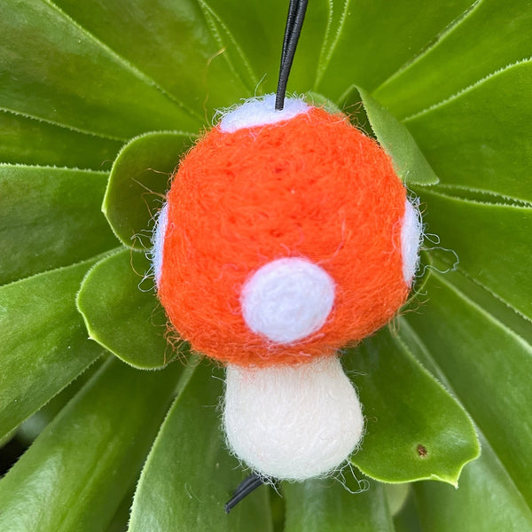 Knitted mushroom ornament on a green leaf background