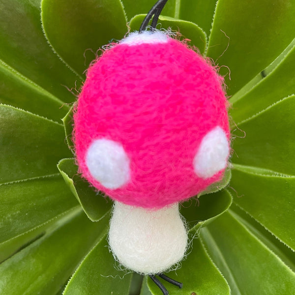 Pink and white mushroom-shaped toy on green leaves