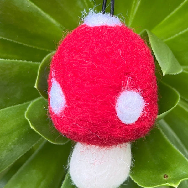 Red and white mushroom-shaped object on a green leafy background