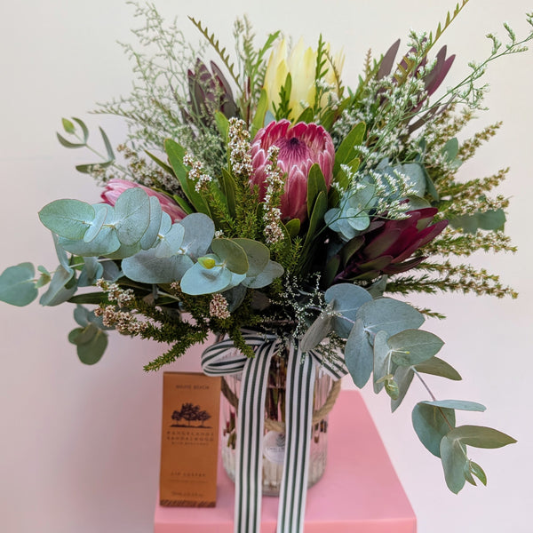 Bouquet of flowers in a striped vase on a pink surface with a blurred background