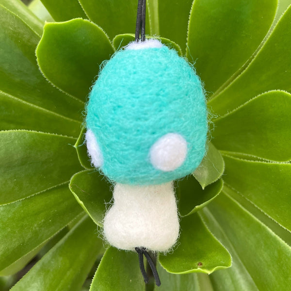 Toy mushroom with a green cap and white stem on green leaves